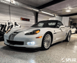 White Corvette C6 60th Anniversary Grand Sport with chrome face wheels in a vehicle gallery setting.
