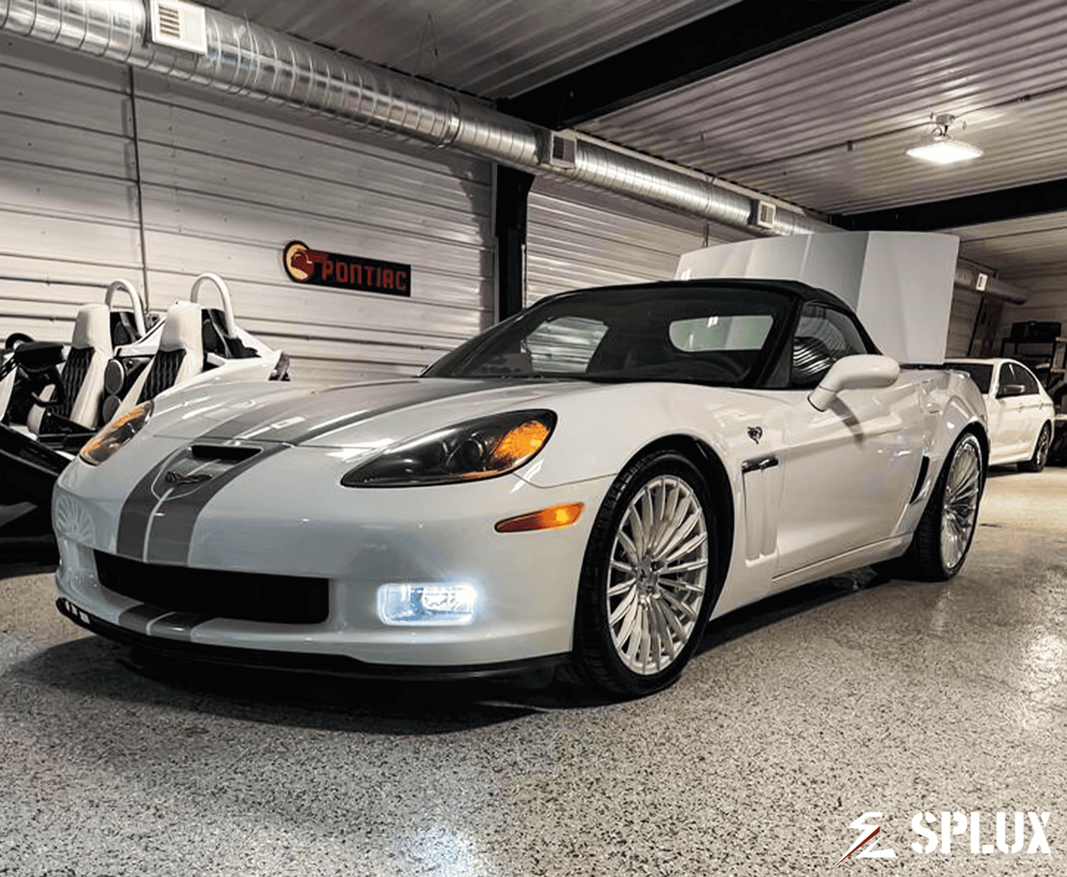 White Corvette C6 60th Anniversary Grand Sport with chrome face wheels in a vehicle gallery setting.