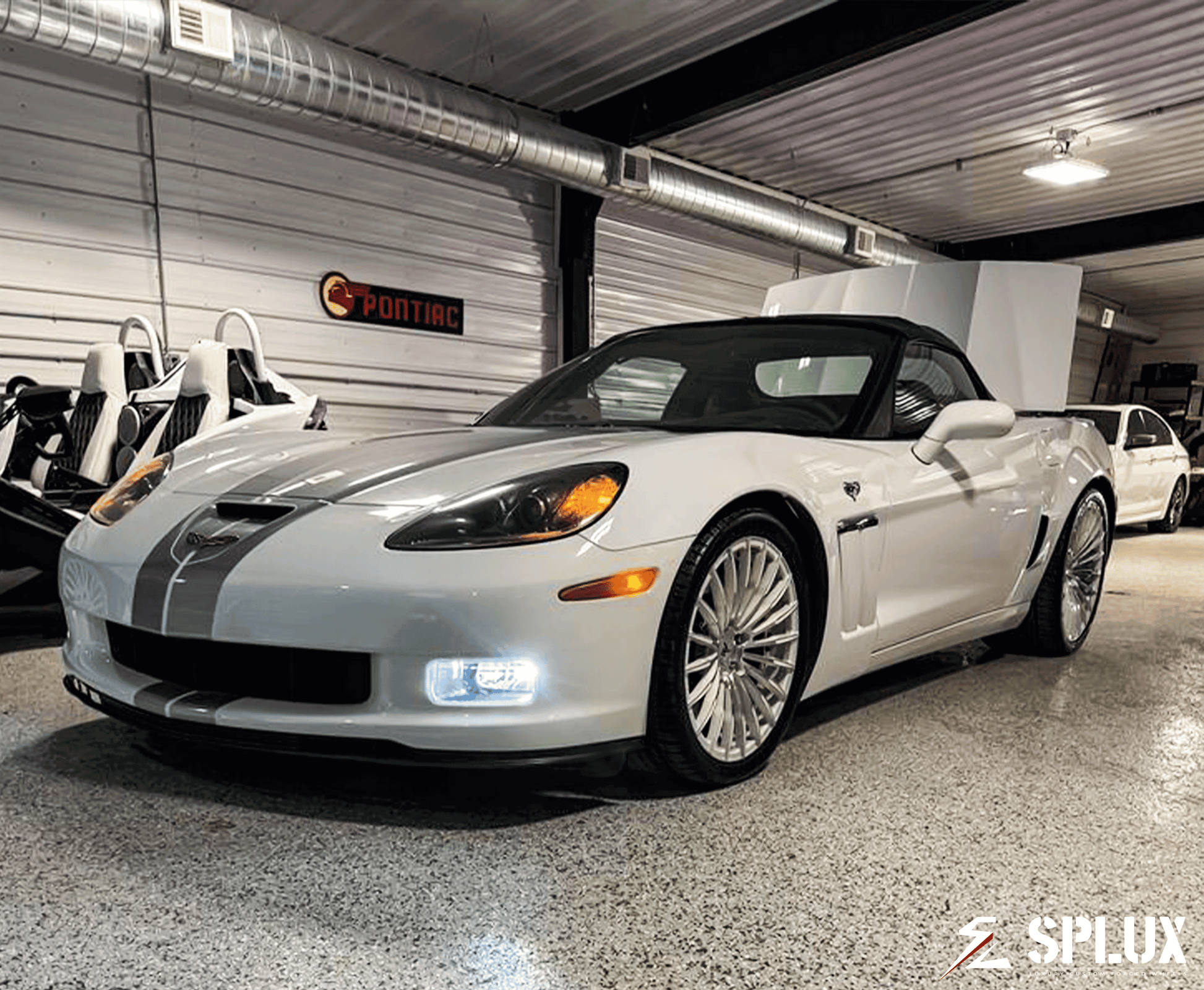 White Corvette C6 60th Anniversary Grand Sport with chrome face wheels in a vehicle gallery setting.