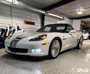 White Corvette C6 60th Anniversary Grand Sport with chrome face wheels in a vehicle gallery setting.