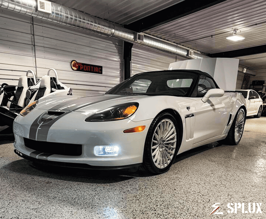 White Corvette C6 60th Anniversary Grand Sport with chrome face wheels in a vehicle gallery setting.